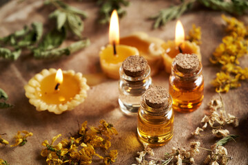 Essential oil bottles with dried herbs and flowers and bees wax candles