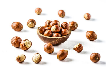 Fototapeta premium Hazelnuts in a wooden bowl on white background