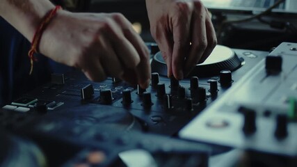DJ carefully twisting the knobs of the mixer console during the live set. Musician is changing the settings of the controller with the hands close up
