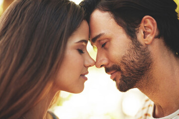 Outdoor, couple and smile with forehead touch in park for bonding, love and affection in Spain. People, relationship and eyes closed for support with care as lovers on break to relax, rest and trust