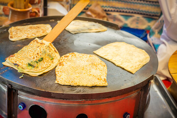 Female hand with a wooden spatula prepares Traditional delicious fresh gozleme. Turkish food concept