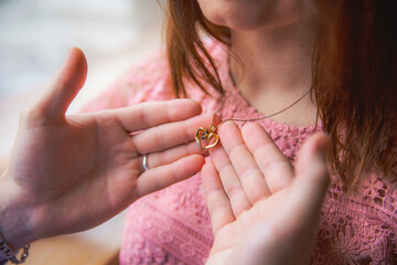 The man touches the girl's heart-shaped amulet, symbolizing his love for her.