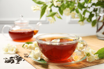 Hot jasmine tea in cup and flowers on white wooden table