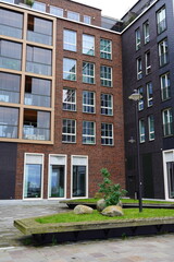 Naklejka premium New modern brown building brick facade with green grass in the front. Tallinn, Estonia, Europe. July 2024.