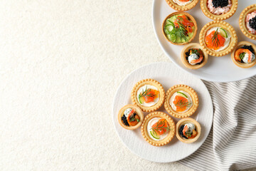 Delicious canapes with shrimps, salmon and caviar on beige textured table, flat lay. Space for text