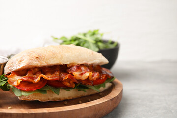 Tasty sandwich with bacon on grey table, closeup. Space for text