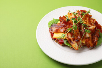 Tasty sandwich with bacon and microgreens on green table. Space for text