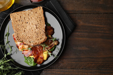Tasty sandwich with bacon and microgreens on wooden table, flat lay. Space for text