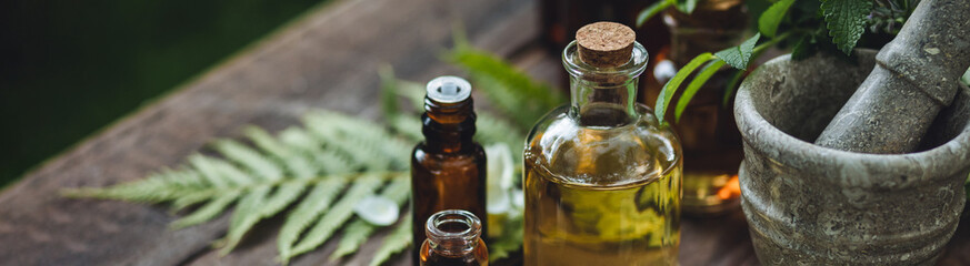 Herbal essential oil in old vintage apothecary glass bottles. Alternative medicine, skin care, aromatherapy and natural organic ingredients for medicine, pharmacy, fragrance cosmetic production banner