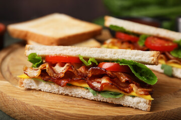 Delicious sandwich with fried bacon on wooden board, closeup