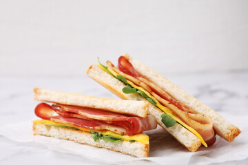 Delicious sandwiches with bacon on white table, closeup