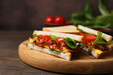 Delicious sandwiches with fried bacon on wooden table, closeup