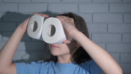 Joking for humor with toilet paper. A child with humor makes a binoculars from the hygiene papers indoor.