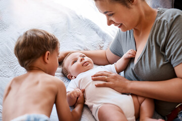 Family, mom and boy children on bed for bonding together, baby support and growth in home. Mother,...