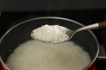 Taking boiled rice from pot with spoon, closeup