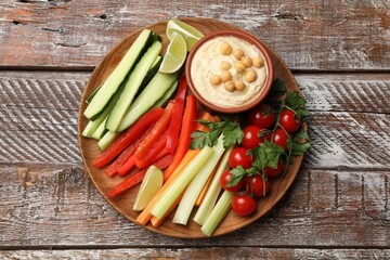 Tasty homemade hummus served with different vegetables on wooden table, top view