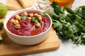 Tasty beet hummus with chickpeas and parsley in bowl on light table, closeup