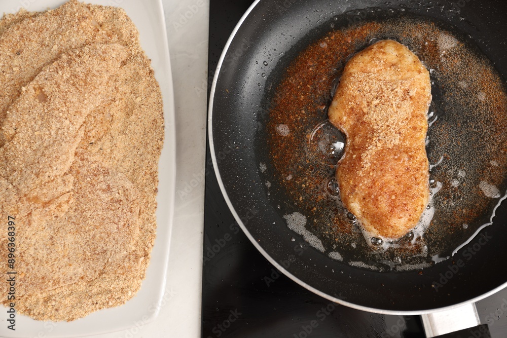 Wall mural Schnitzel cooking in frying pan on stove, top view