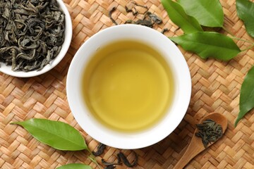 Refreshing green tea in cup, spoon and leaves on table, flat lay