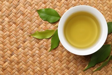 Refreshing green tea in cup and leaves on table, flat lay. Space for text