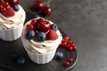 Tasty cupcakes with different berries on grey table, closeup. Space for text