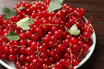 Fresh red currants and leaves on wooden table, closeup