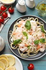 Tasty pasta with shrimps served on light blue wooden table, flat lay
