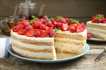 Tasty sponge cake with fresh berries and mint on wooden table, closeup