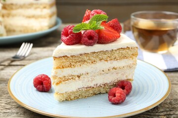 Piece of tasty sponge cake with fresh berries and mint on wooden table, closeup