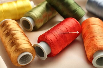 Spools of sewing threads on beige cloth, closeup