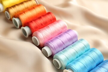 Spools of sewing threads on beige cloth, closeup