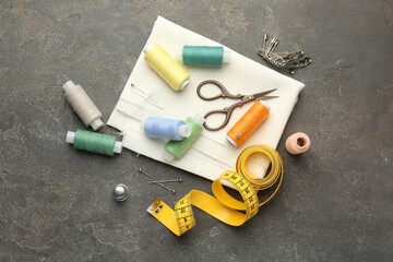 Flat lay composition with different sewing supplies on grey textured table