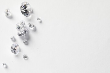 Many beautiful shiny diamonds on white background, flat lay. Space for text