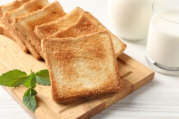 Delicious toasts with milk on white wooden table, closeup
