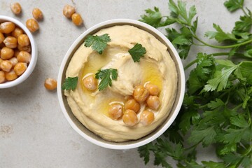 Delicious hummus with olive oil, chickpeas and parsley on light grey table, flat lay