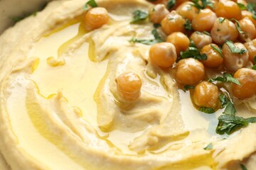 Delicious hummus with olive oil, chickpeas and parsley, closeup