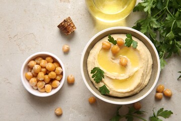 Delicious hummus with olive oil, chickpeas and parsley on light textured table, flat lay