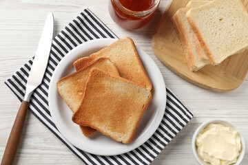 Delicious toasted bread slices served on white wooden table, flat lay