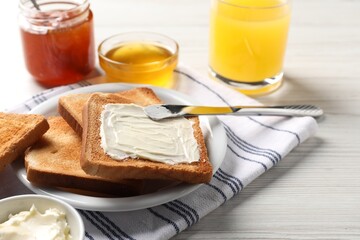 Delicious toasted bread slices with butter served on white wooden table