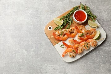 Skewers with delicious grilled shrimps served on grey table, top view. Space for text