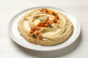 Delicious hummus with olive oil, chickpeas and paprika on white wooden table