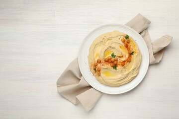 Delicious hummus with olive oil, chickpeas and paprika on white wooden table, top view. Space for text