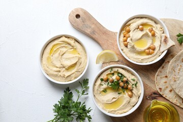 Delicious hummus with olive oil and chickpeas served on white table, flat lay