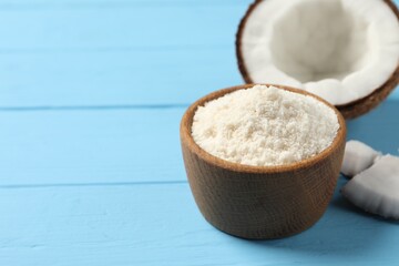 Fresh coconut flour in bowl and nut on light blue wooden table, space for text
