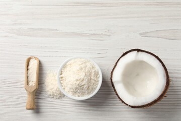 Fresh coconut flour in bowl, scoop and nut on white wooden table, flat lay