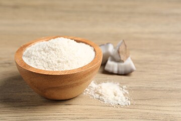 Fresh coconut flour in bowl and nut on wooden table