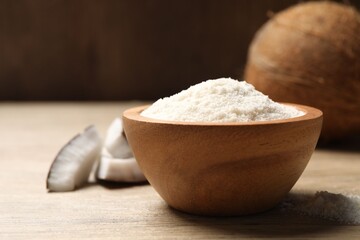 Fresh coconut flour in bowl and nut on wooden table