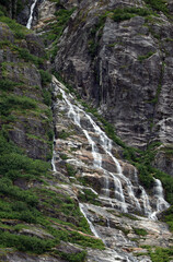Waterfall running down rock face in Alaska mountains.