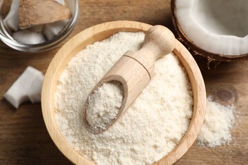 Coconut flour in bowl, scoop and fresh fruits on wooden table, flat lay