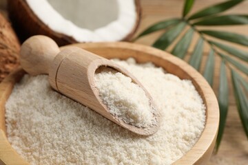 Coconut flour in bowl and scoop on table, closeup